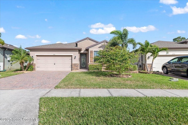 single story home with a front lawn, decorative driveway, an attached garage, and stucco siding