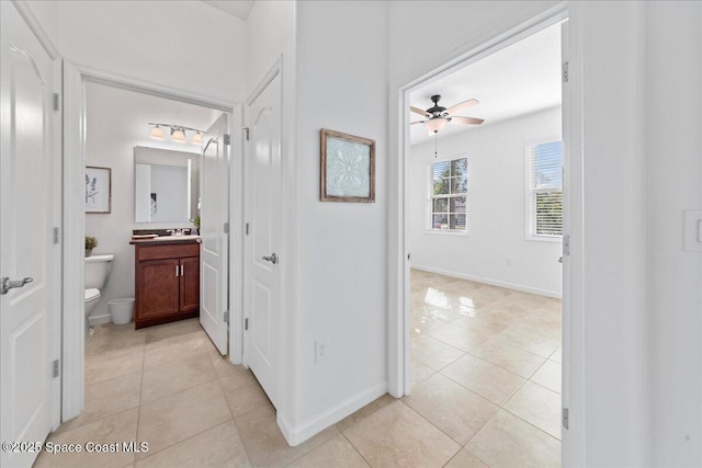 hall featuring baseboards and light tile patterned floors