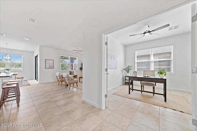 home office with ceiling fan, light tile patterned floors, visible vents, and a healthy amount of sunlight