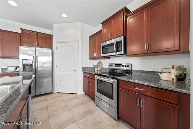 kitchen featuring light tile patterned floors, appliances with stainless steel finishes, dark stone counters, and recessed lighting