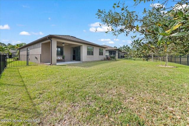 back of property with a lawn, a patio, a fenced backyard, ceiling fan, and stucco siding