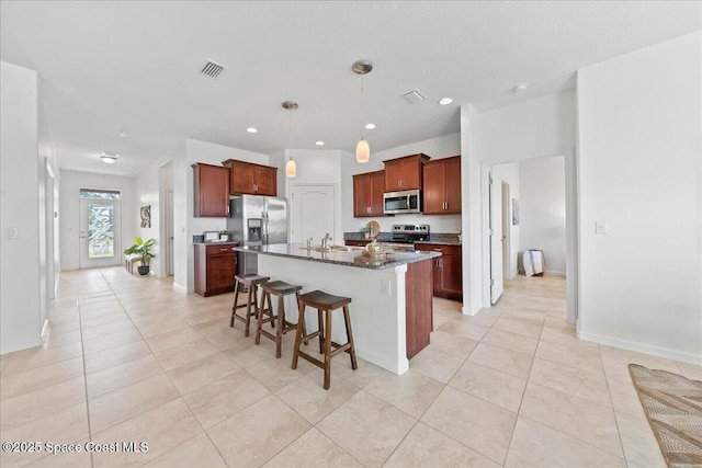 kitchen with appliances with stainless steel finishes, visible vents, a kitchen breakfast bar, and light tile patterned flooring