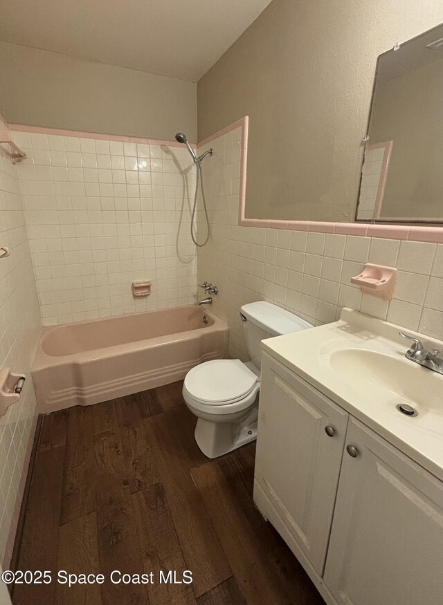 1341 S Patrick Dr, Satellite Beach, FL 32937 - bathroom with toilet, wood finished floors, bathtub / shower combination, vanity, and tile walls