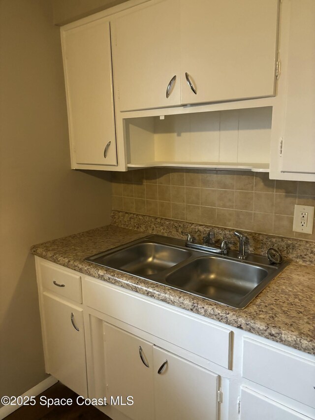 1341 S Patrick Dr, Satellite Beach, FL 32937 - kitchen featuring backsplash, a sink, and white cabinetry