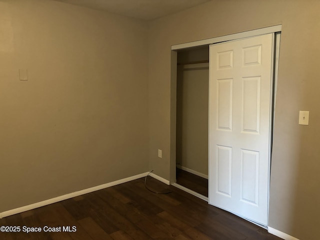 1341 S Patrick Dr, Satellite Beach, FL 32937 - unfurnished bedroom with dark wood-style flooring, a closet, and baseboards