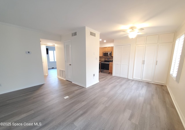 unfurnished living room featuring a wealth of natural light, visible vents, and wood finished floors