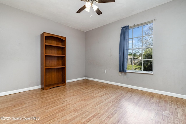 spare room featuring baseboards, ceiling fan, and light wood finished floors