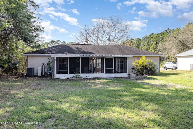 rear view of property featuring a sunroom, a lawn, and stucco siding