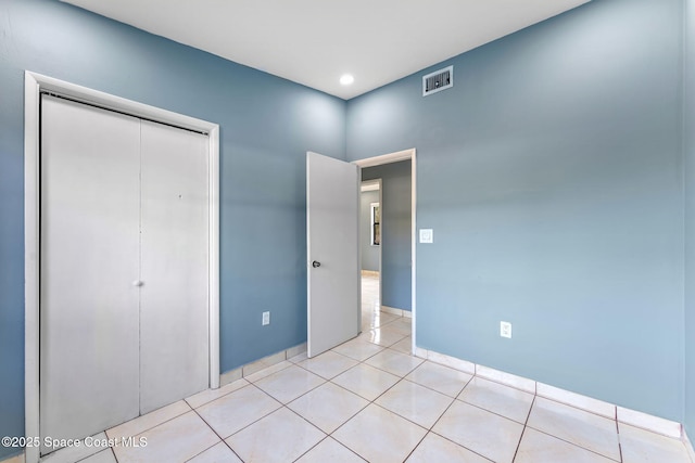 unfurnished bedroom featuring light tile patterned floors, a closet, and visible vents