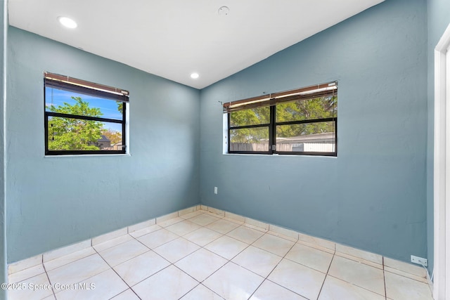 tiled spare room featuring vaulted ceiling, recessed lighting, and a healthy amount of sunlight