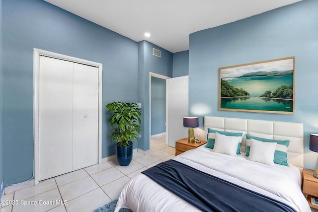 tiled bedroom with a closet, visible vents, and baseboards