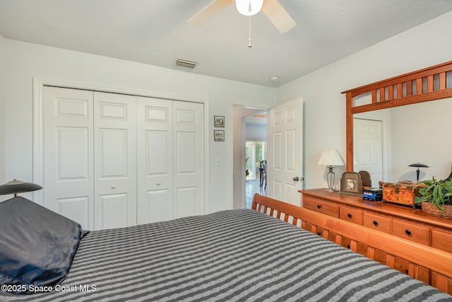 bedroom featuring a textured ceiling, a closet, visible vents, and a ceiling fan