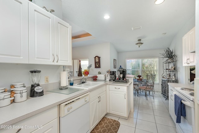 kitchen featuring white appliances, light tile patterned floors, a peninsula, white cabinetry, and a sink