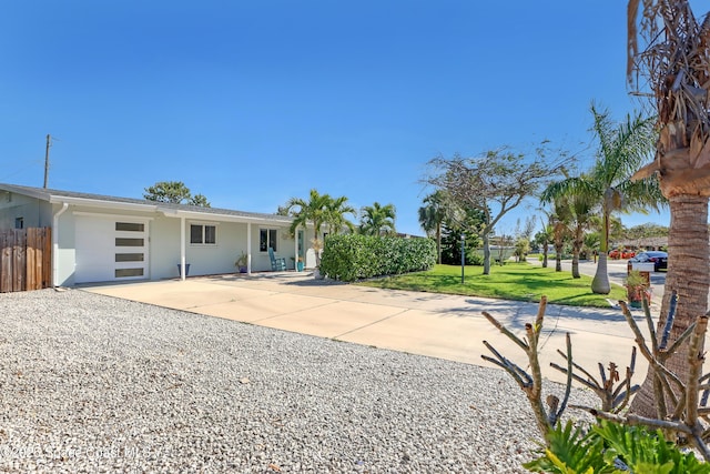 view of front of home with a garage, fence, concrete driveway, stucco siding, and a front yard