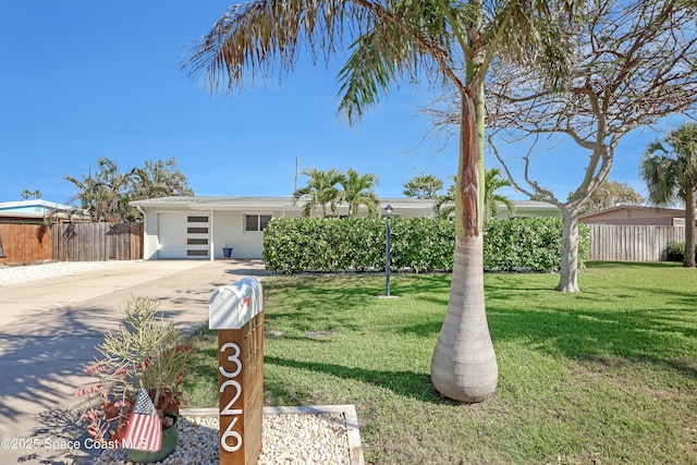 view of front facade featuring driveway, a garage, fence, and a front lawn