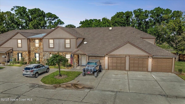 townhome / multi-family property featuring stone siding, roof with shingles, driveway, and an attached garage