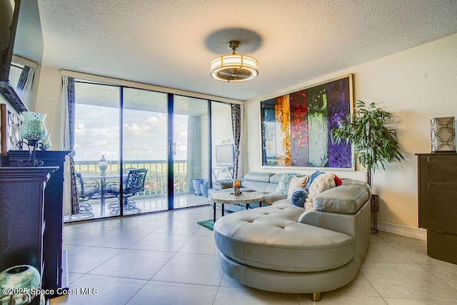 living room with a textured ceiling, a wall of windows, tile patterned flooring, and baseboards