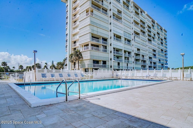 community pool with a patio and fence