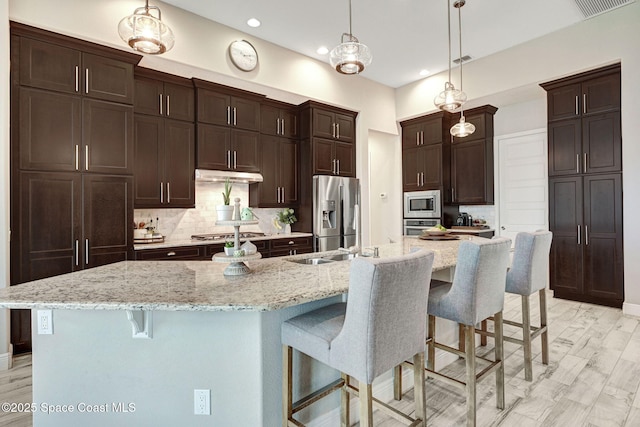 3882 Durksly Dr, Melbourne, FL 32940 - kitchen featuring decorative backsplash, appliances with stainless steel finishes, dark brown cabinets, under cabinet range hood, and a kitchen bar