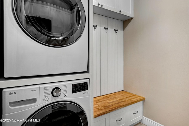 3882 Durksly Dr, Melbourne, FL 32940 - clothes washing area featuring stacked washer / dryer, cabinet space, and baseboards