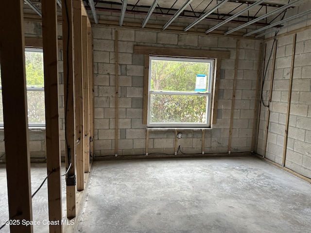 interior space featuring concrete block wall and unfinished concrete flooring