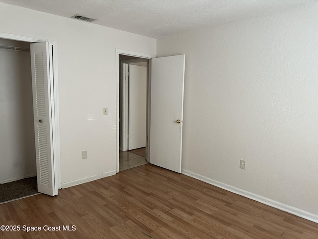 unfurnished bedroom featuring a closet, baseboards, and wood finished floors