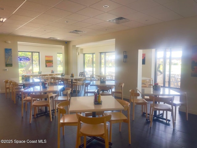 dining area featuring a drop ceiling, visible vents, and a healthy amount of sunlight