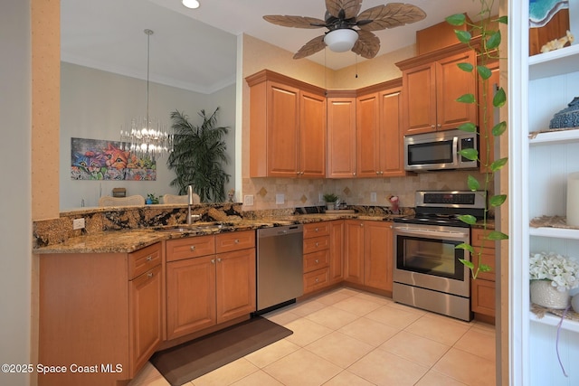 kitchen with crown molding, light tile patterned floors, appliances with stainless steel finishes, a sink, and dark stone counters