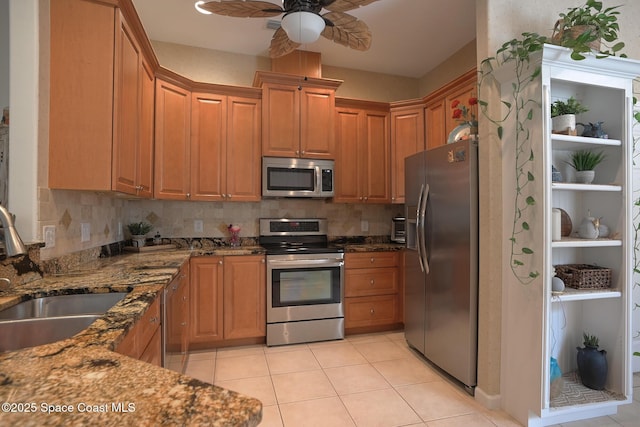 kitchen with light tile patterned floors, appliances with stainless steel finishes, dark stone countertops, a sink, and backsplash