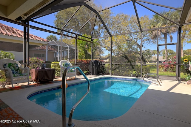 outdoor pool with glass enclosure and a patio