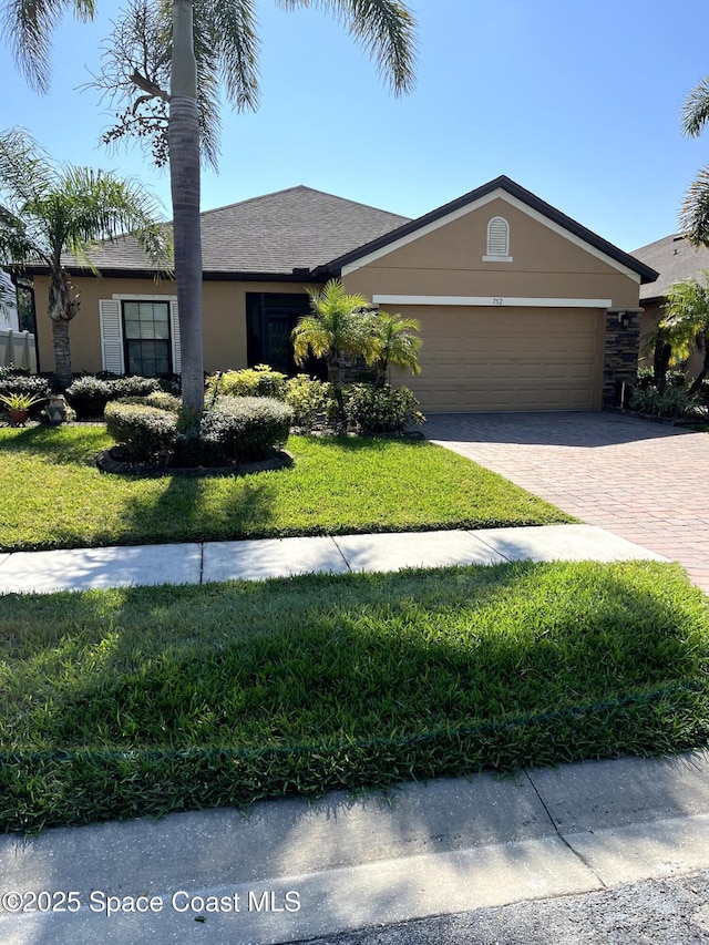 view of front of house with an attached garage, a front yard, decorative driveway, and stucco siding