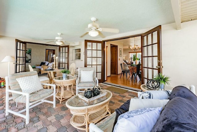 living room with ceiling fan with notable chandelier and french doors