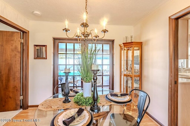 dining room featuring baseboards, ornamental molding, and an inviting chandelier