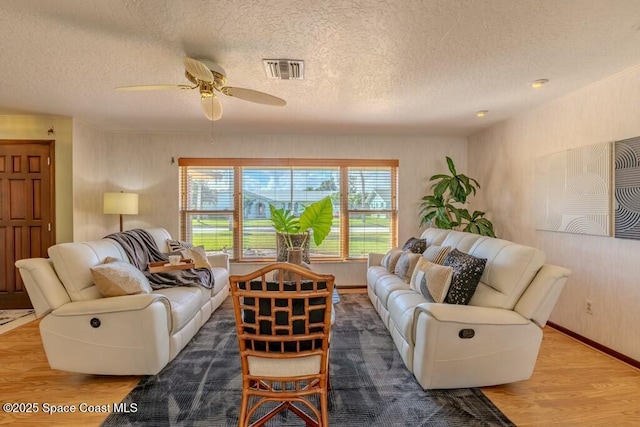 living area with a ceiling fan, visible vents, a textured ceiling, and wood finished floors