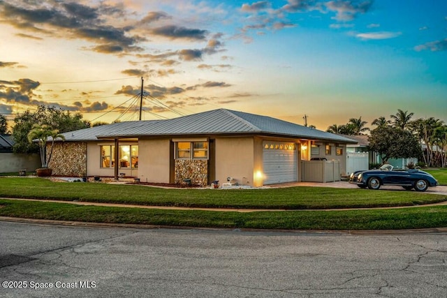 view of front of home featuring metal roof, a garage, concrete driveway, stucco siding, and a front lawn