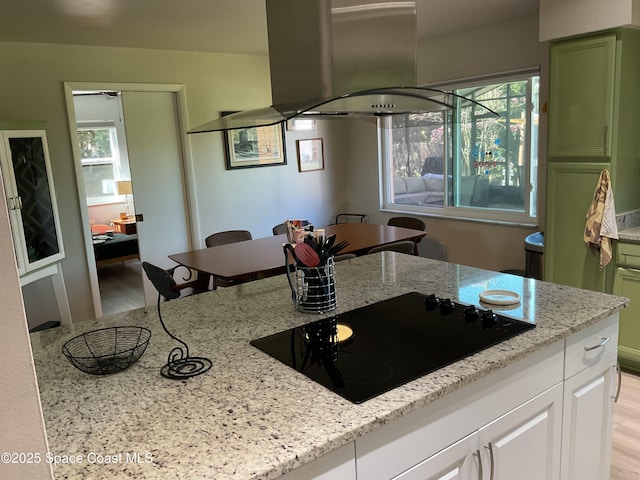 kitchen featuring light wood-style floors, light stone counters, black electric cooktop, and green cabinetry