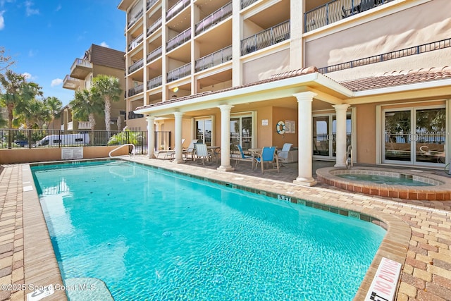 pool with fence, a community hot tub, and a patio