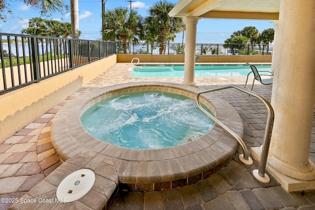 community pool featuring a hot tub, fence, and a patio