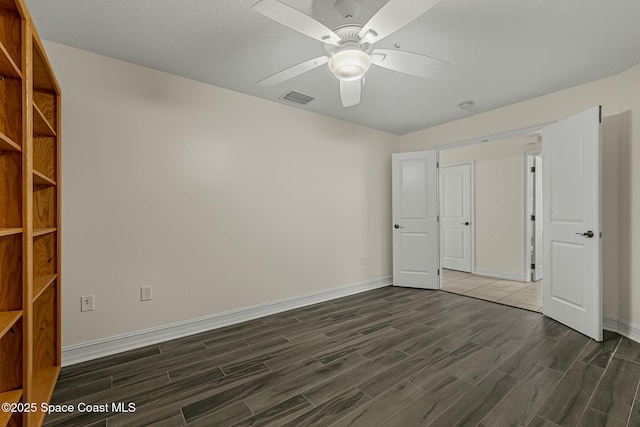 unfurnished bedroom featuring dark wood-style floors, ceiling fan, visible vents, and baseboards