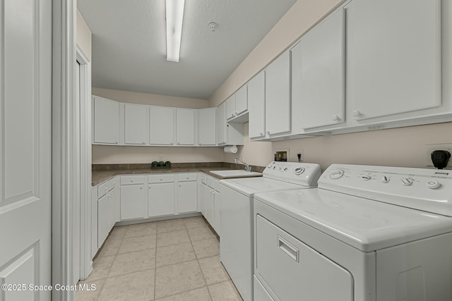 washroom featuring light tile patterned floors, a textured ceiling, a sink, washer and dryer, and cabinet space