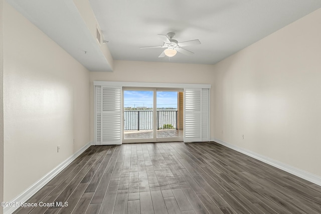 empty room featuring dark wood finished floors, baseboards, and ceiling fan