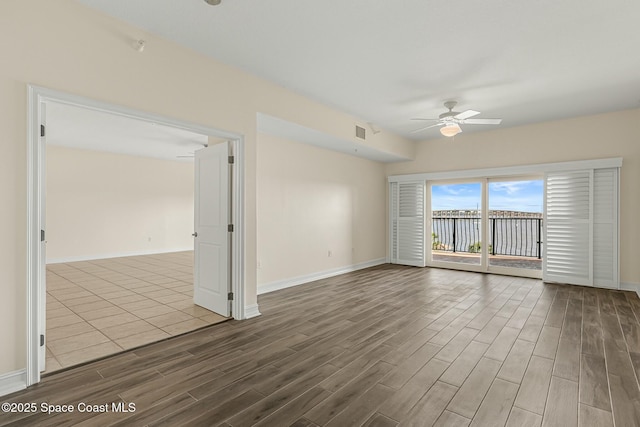 unfurnished room with baseboards, ceiling fan, visible vents, and wood finished floors