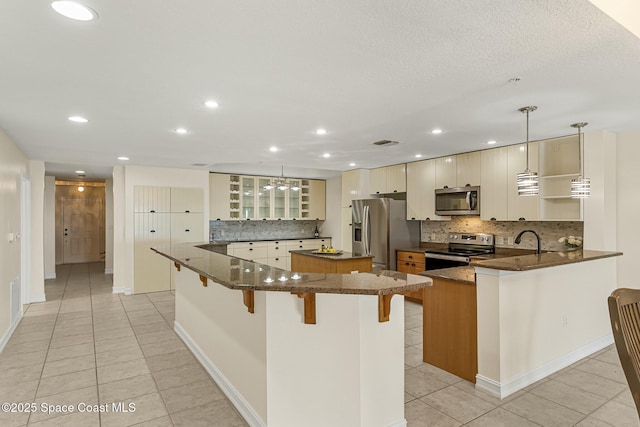 kitchen with stainless steel appliances, a breakfast bar, a large island, and light tile patterned floors