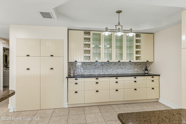 kitchen featuring visible vents, dark countertops, cream cabinets, backsplash, and light tile patterned flooring