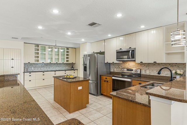 kitchen featuring open shelves, stainless steel appliances, visible vents, a sink, and dark stone counters