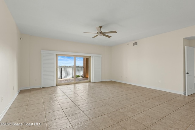 empty room with light tile patterned floors, ceiling fan, visible vents, and baseboards