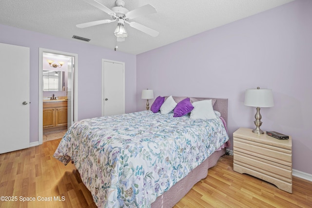 bedroom featuring visible vents, a sink, a textured ceiling, and light wood finished floors