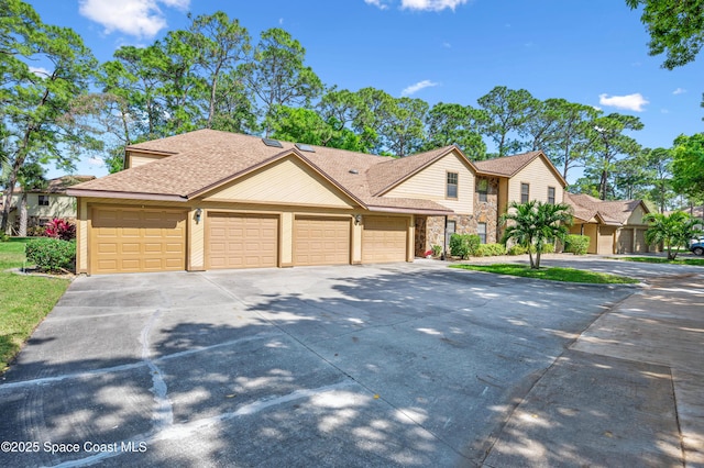 view of front of home with stone siding, roof with shingles, driveway, and an attached garage