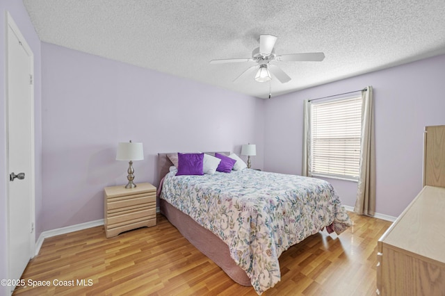 bedroom featuring baseboards, light wood-style flooring, and a textured ceiling