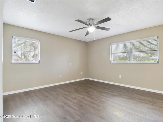 unfurnished room featuring a textured ceiling, baseboards, and wood finished floors